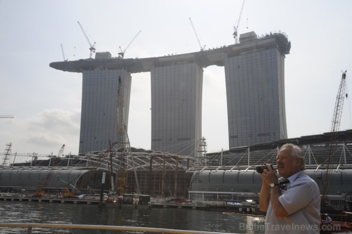 Marina Bay Sands būvprojekts. No 2012. gada pretendē uz lielāko viesnīcas statusu visā pasaulē. Augšā ir baseins, kas atrodas starp visiem šiem trim t Marina Bay Sands būvprojekts. No 2012. gada pretendē uz lielāko viesnīcas statusu visā pasaulē. Augšā ir baseins, kas atrodas starp visiem šiem trim t 89583